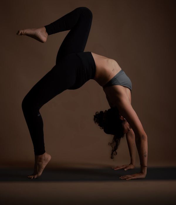 Woman practicing balance yoga pose in a dark studio setting.